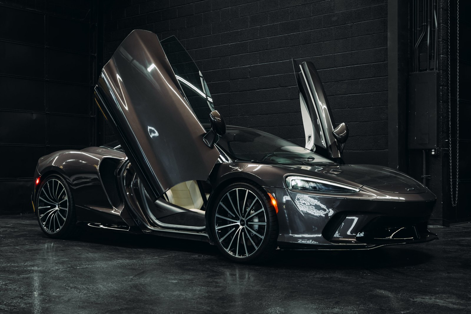 McLaren GT in a sleek dark setting with dihedral doors open, showcasing luxury design and performance features, available for rent in Scottsdale, AZ.