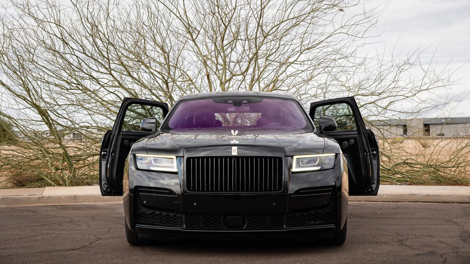 Luxury Rolls-Royce Cullinan SUV with open doors parked against a desert backdrop, showcasing high-end design and elegance for luxury car rentals in Scottsdale, Arizona.