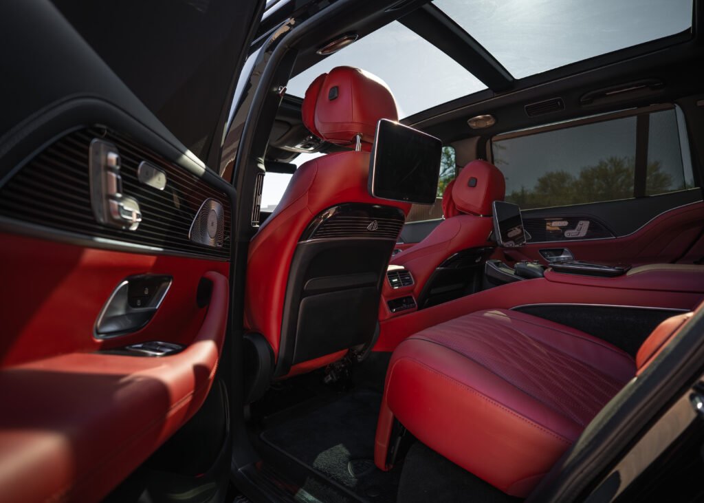 Interior of a Mercedes-Benz GLS 600 Maybach featuring luxurious red leather seats, advanced technology displays, and panoramic sunroof, emphasizing high-end SUV comfort and style for rental in Scottsdale or Phoenix.