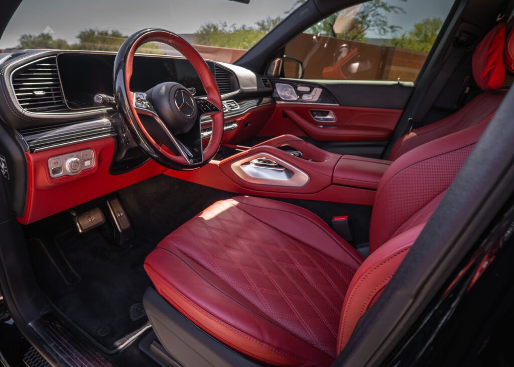 Interior of a Mercedes-Benz GLS 600 Maybach showcasing luxurious red leather seats, modern dashboard with digital displays, and high-end finishes, emphasizing premium SUV rental experience in Scottsdale.