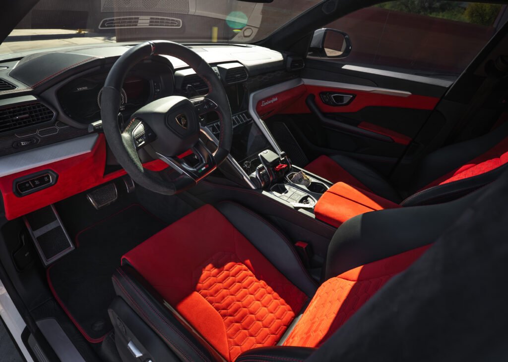 Lamborghini Urus interior showcasing premium red and black leather upholstery, sporty steering wheel, advanced dashboard, and luxurious cabin design, emphasizing luxury SUV features for rent in Scottsdale and Phoenix.