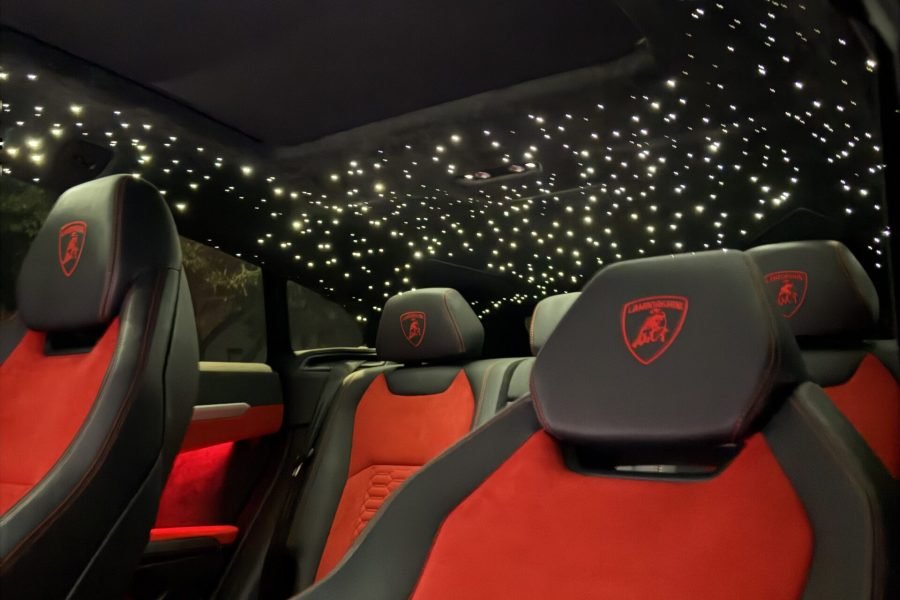 Lamborghini Urus interior featuring luxurious red and black leather seats, illuminated starry ceiling, and premium detailing, emphasizing the luxury experience available through Apex Exotic Rentals.