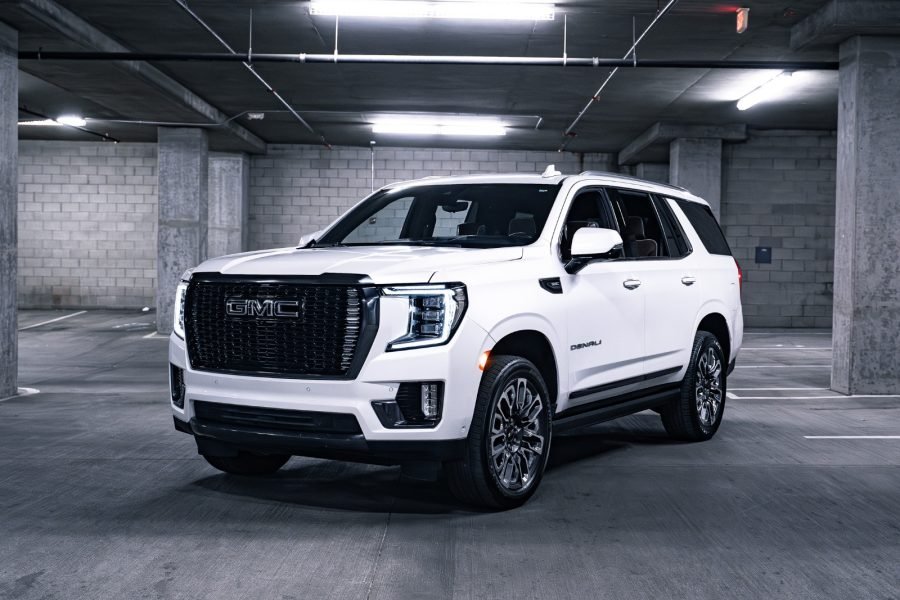 GMC Yukon Denali Ultimate SUV parked in a dimly lit garage, showcasing its luxury design, bold grille, and chrome accents, highlighting features relevant to luxury car rentals in Scottsdale.