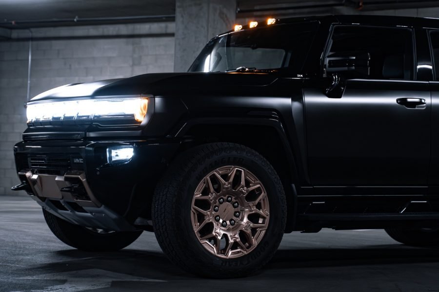 Hummer EV 3X in a parking garage, showcasing bold black exterior, bronze wheels, and bright LED headlights, emphasizing luxury and off-road capabilities for rentals in Scottsdale.
